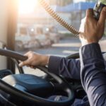 Truck driver speaking into radio on the road.