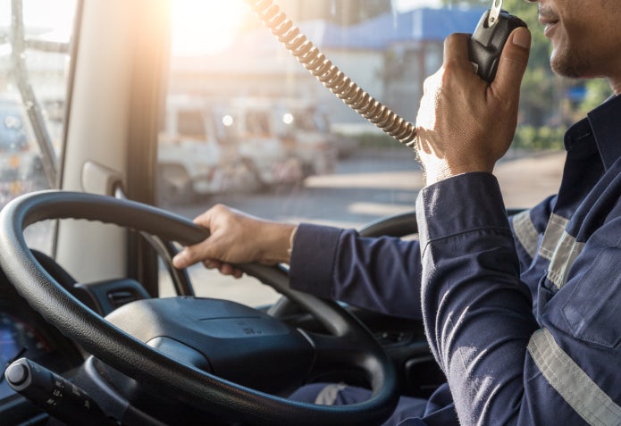 Truck driver speaking into radio on the road.